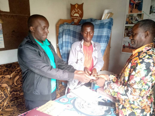 Der Partnerschaftskoordinator Javani Ngumbuke übergibt die Rogatekollekte an Pfarrer Mkolanundzi in Ukalawa im Beisein der Schatzmeisterin Debora Lyabonga.